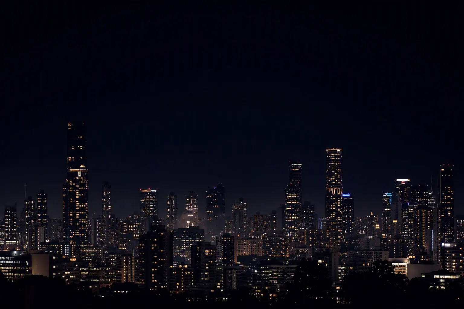 Melbourne skyline at night with hundreds of warm golden lit windows across dark towers